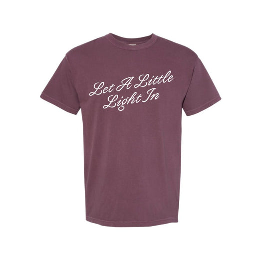 Garment-dyed vintage fuchsia T-shirt with "Let A Little Light In" printed across the front.